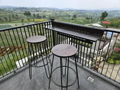 Dua meja bar di balkon villa, menghadap hamparan ladang dan perbukitan Guci