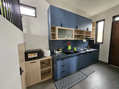 Dapur villa dengan kabinet biru, kompor, microwave, dan rak penyimpanan