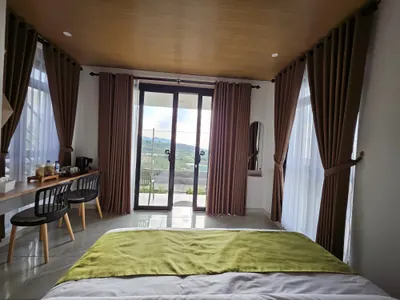 Kamar tidur dengan pintu kaca menuju balkon pribadi dan meja kecil di sudut kamar