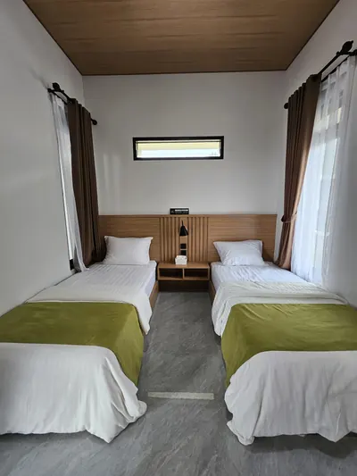 Kamar tidur dua single bed dengan nakas dan jendela menghadap luar