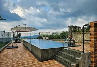Kolam renang infinity air panas alami Del Luna dengan payung dan dek kayu, menghadap perbukitan Guci