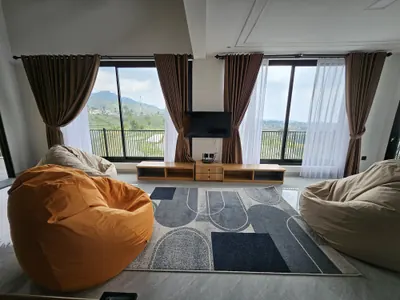 Ruang santai dengan bean bag, karpet, dan jendela lebar menghadap ladang terasering