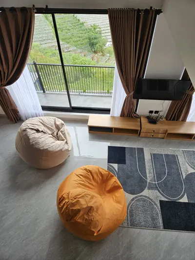 Sudut santai dengan bean bag menghadap jendela besar dan pemandangan perbukitan