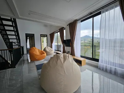 Ruang santai lantai atas dengan bean bag dan tangga besi menuju rooftop